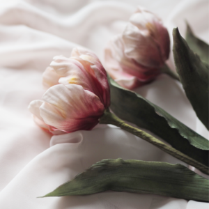 2 pink tulip sugar flowers with green leaves lying on pink chiffon