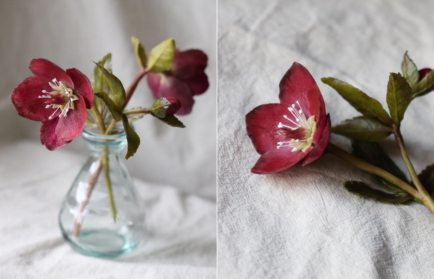 A burgundy hellebore crafted from cold porcelain clay in a vase; a cold porcelain hellebore lying on a neutral table cloth
