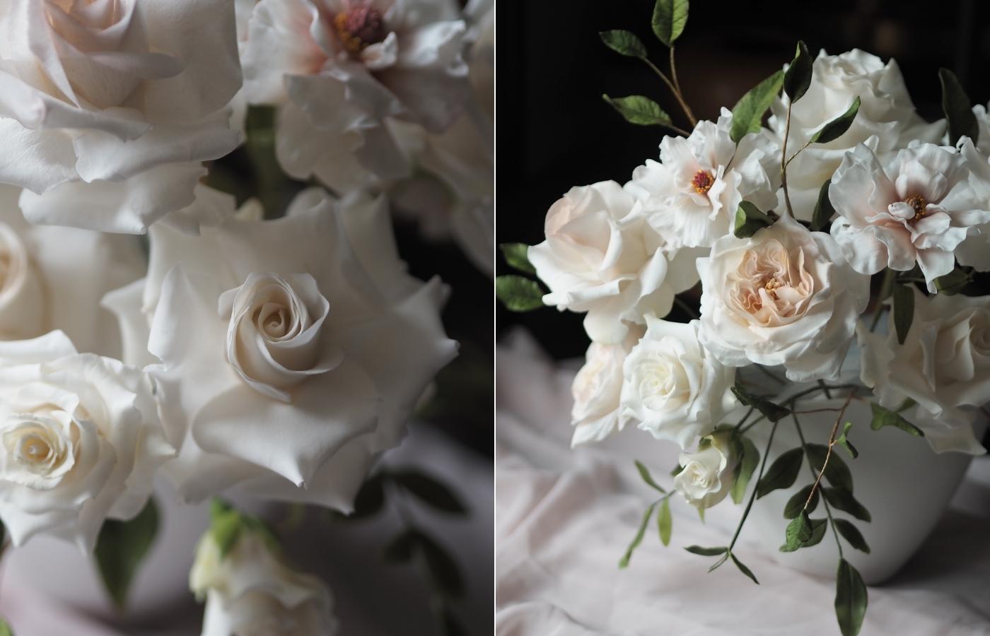 white handcrafted sugar flowers: a collection of roses in a vase against a dark background